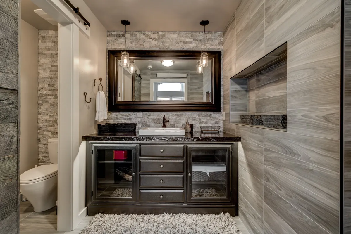 A well-lit bathroom showcasing a modern vanity with a large mirror and pendant lights, exuding a calm and sophisticated mood. The clean lines and thoughtful lighting suggest recent renovations and a blend of style and functionality.