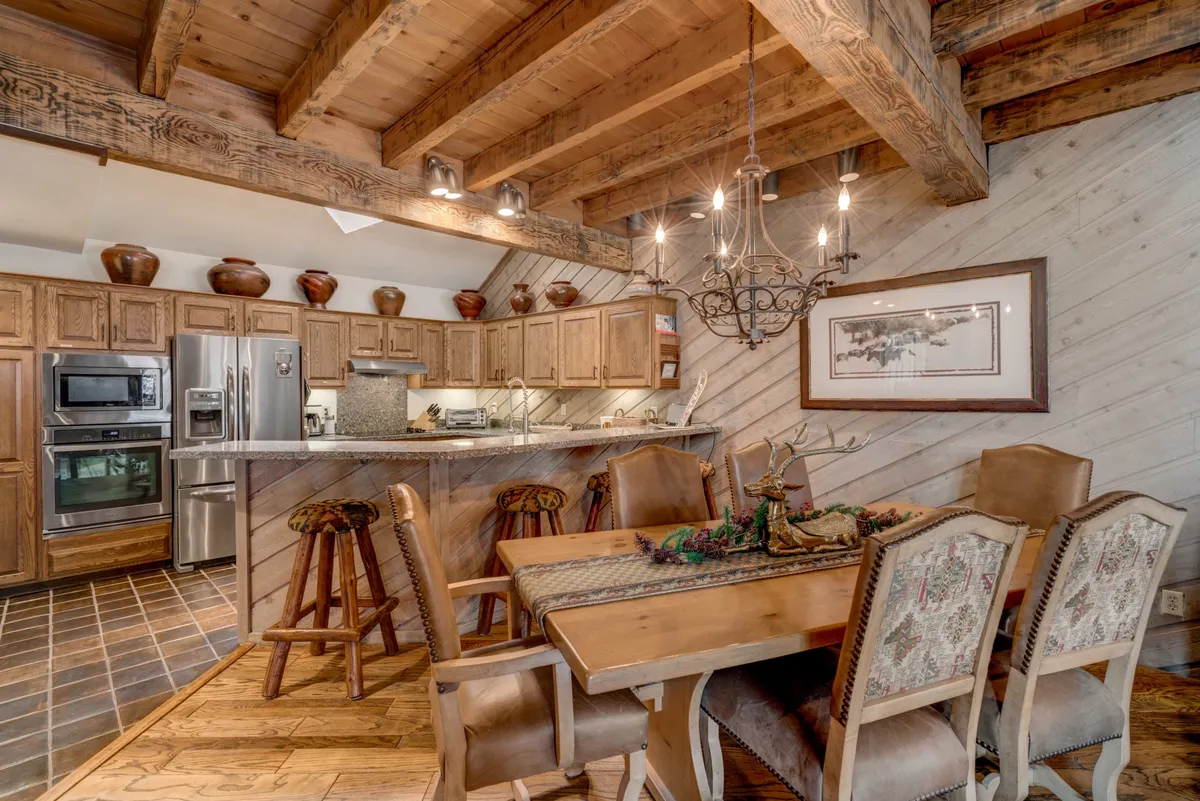 A cozy dining area with a rustic wooden table, a glowing chandelier, and cabinetry. The decor and setup signal a family-friendly, communal space, ideal for gathering after outdoor adventures.