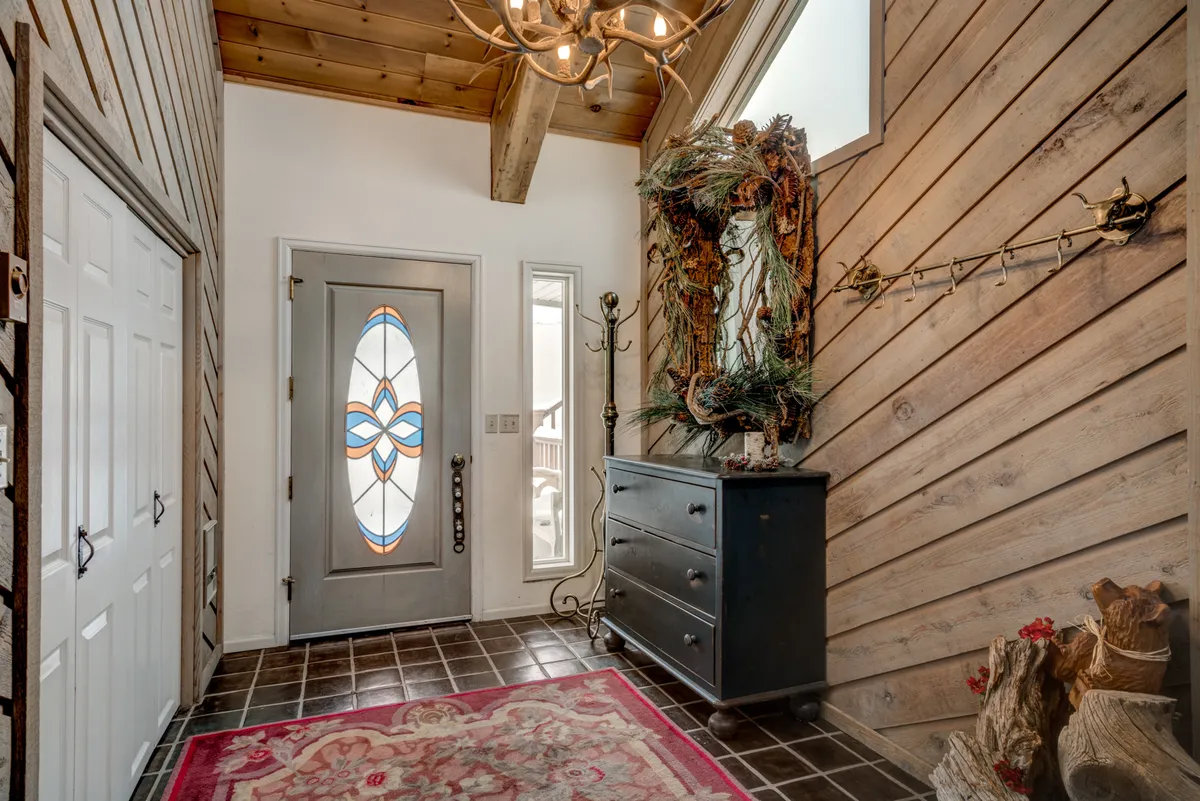 An inviting entryway featuring a decorative wooden door, warm paneling, a soft rug, and a chest of drawers. The space feels homey and welcoming, setting the tone for the rest of the property.
